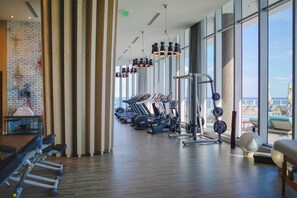 A gym with exercise equipment, large windows, and a brick wall. - Opulent Three Bedroom Condo Panoramic Ocean Views (Hollywood)
