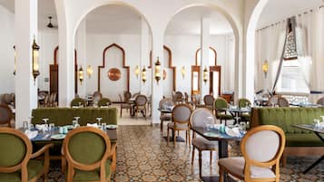 A restaurant with multiple dining areas, including booths and tables, with patterned flooring and traditional decor.