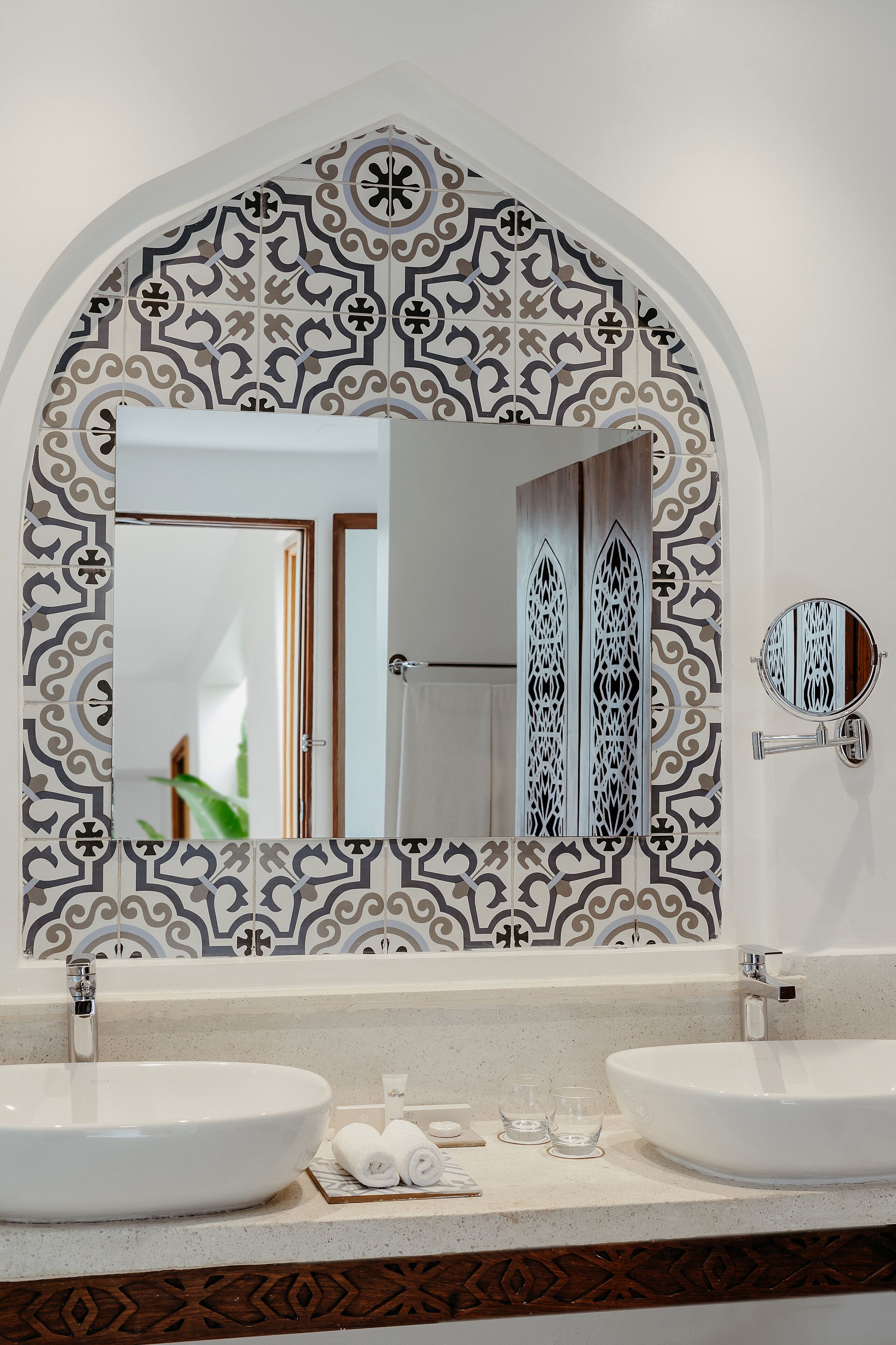 Een badkamer met twee wasbakken, een grote spiegel en decoratieve tegels.