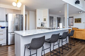 A modern kitchen with a large island, bar stools, stainless steel appliances, and a wooden floor. - Gorgeous, spacious 4 bedroom home in Wintergreen Resort (Roseland)