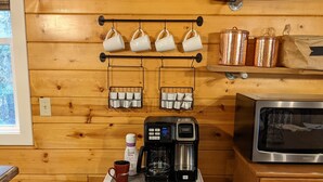 Pared de madera con un letrero que dice 'Coffee', tazas y equipo para preparar café.