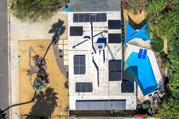 Ein Luftbild eines Wohnhauses mit Solaranlage, Schwimmbad und Terrassenbereich.