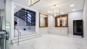 A spacious lobby with marble flooring, a staircase, and modern lighting fixtures. - Nomah - Aptos por Temporada na Consolação (São Paulo)
