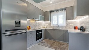 A modern kitchen with a built-in refrigerator, oven, microwave, and a water dispenser. - Thomas House (Corfu)