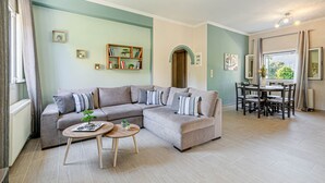 A living room with a sectional sofa, a dining table with chairs, and a small coffee table. - Thomas House (Corfu)