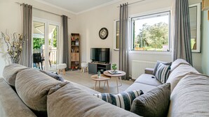 A living room with a sofa, a television, a small table, and a bookshelf. - Thomas House (Corfu)