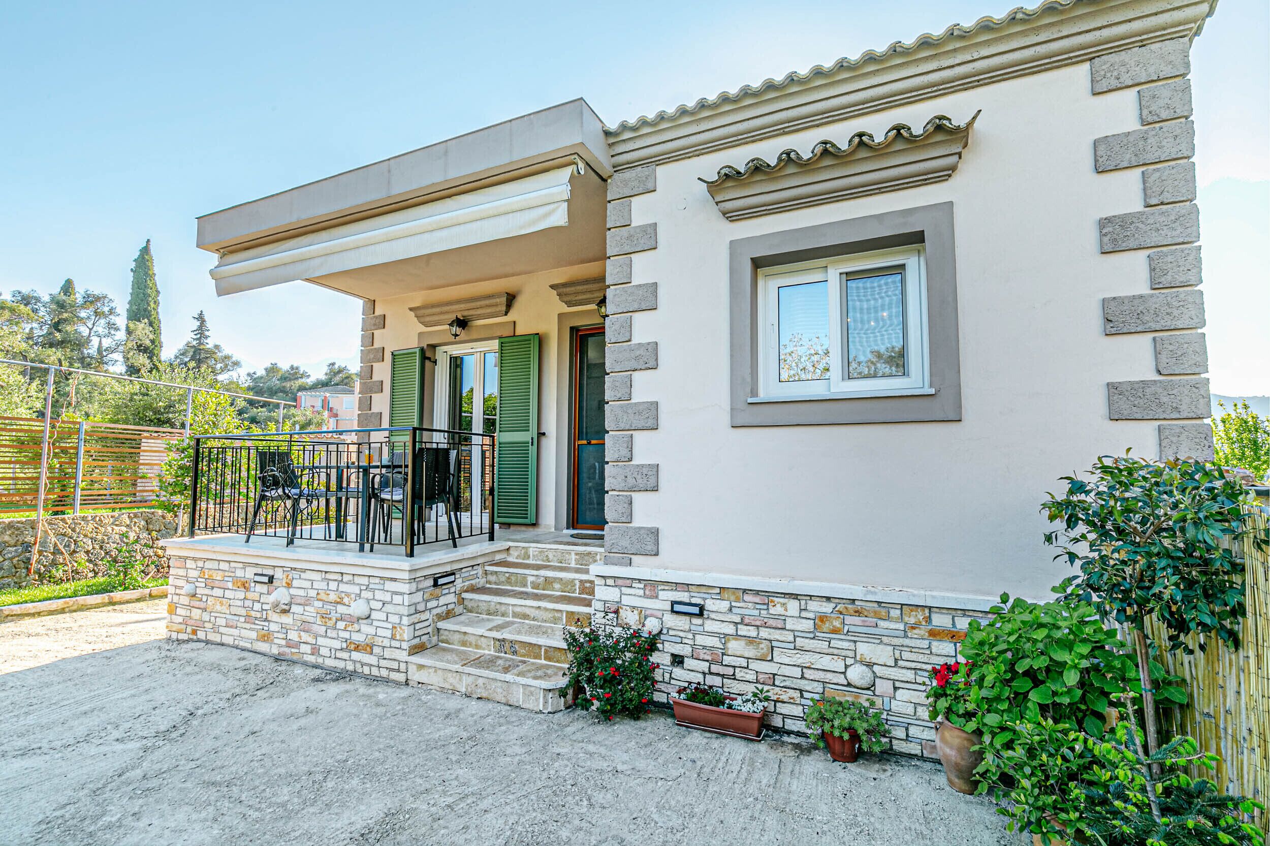 A two-story house with a balcony, a stone facade, and a small garden area.