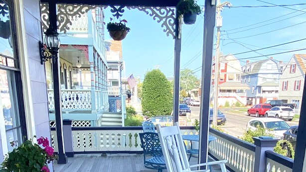 A wooden deck with white rocking chairs and a hanging planter.