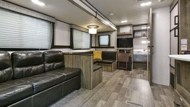 A compact RV interior with a sofa, kitchenette, and a bed. - Givens Glamper Heartland W 3 Beds, Outdoor Pool, Views for Days (Branson)