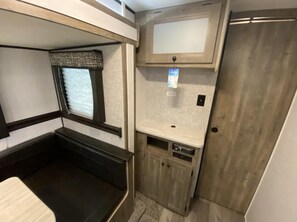 A compact RV interior with a bunk bed, a small kitchenette, and a door. - Givens Glamper Heartland W 3 Beds, Outdoor Pool, Views for Days (Branson)