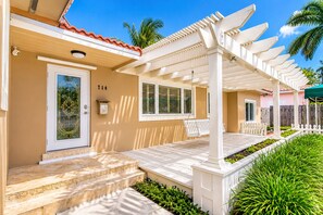 A house with a porch, a door with a number, and a window with shutters.