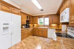 A kitchen with granite countertops, wooden cabinets, a built-in dishwasher, and a microwave.