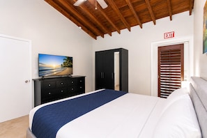 Un dormitorio con cama, televisor en una cómoda, armario y señal de salida.