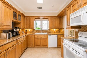 A kitchen with wooden cabinets, a dishwasher, a stove, and a coffee maker.