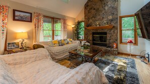 A cozy living room with a stone fireplace, a sofa, a coffee table, and a rug.