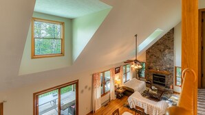 A spacious loft-style room with a stone fireplace, large windows, and a cozy seating area.