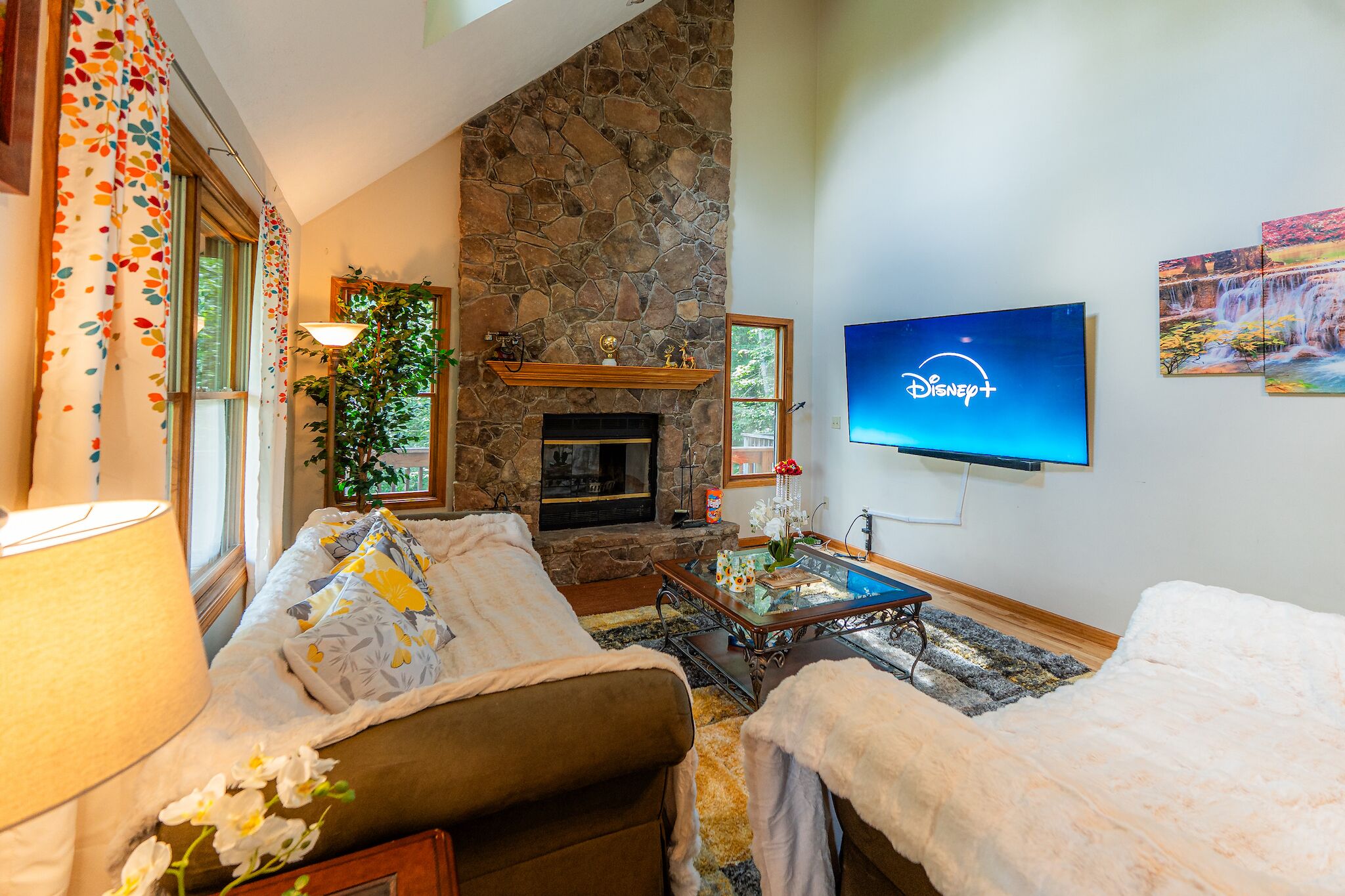 A cozy living room with a stone fireplace, a flat-screen TV, and comfortable seating.