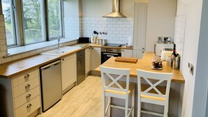 Une cuisine moderne dotée d’une grande fenêtre, de meubles blancs et d’un îlot central agrémenté de tabourets de bar.