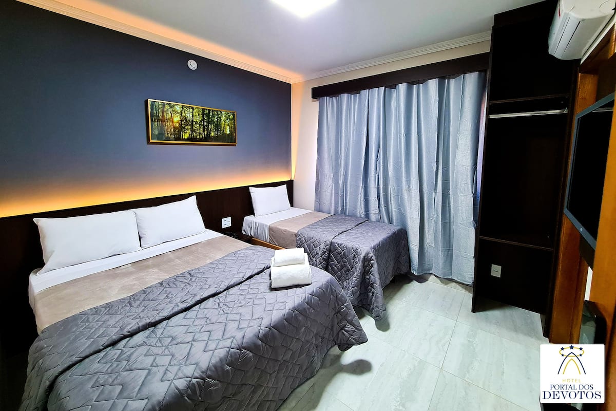 A hotel room with two beds, a painting on the wall, a clock, and a wardrobe.