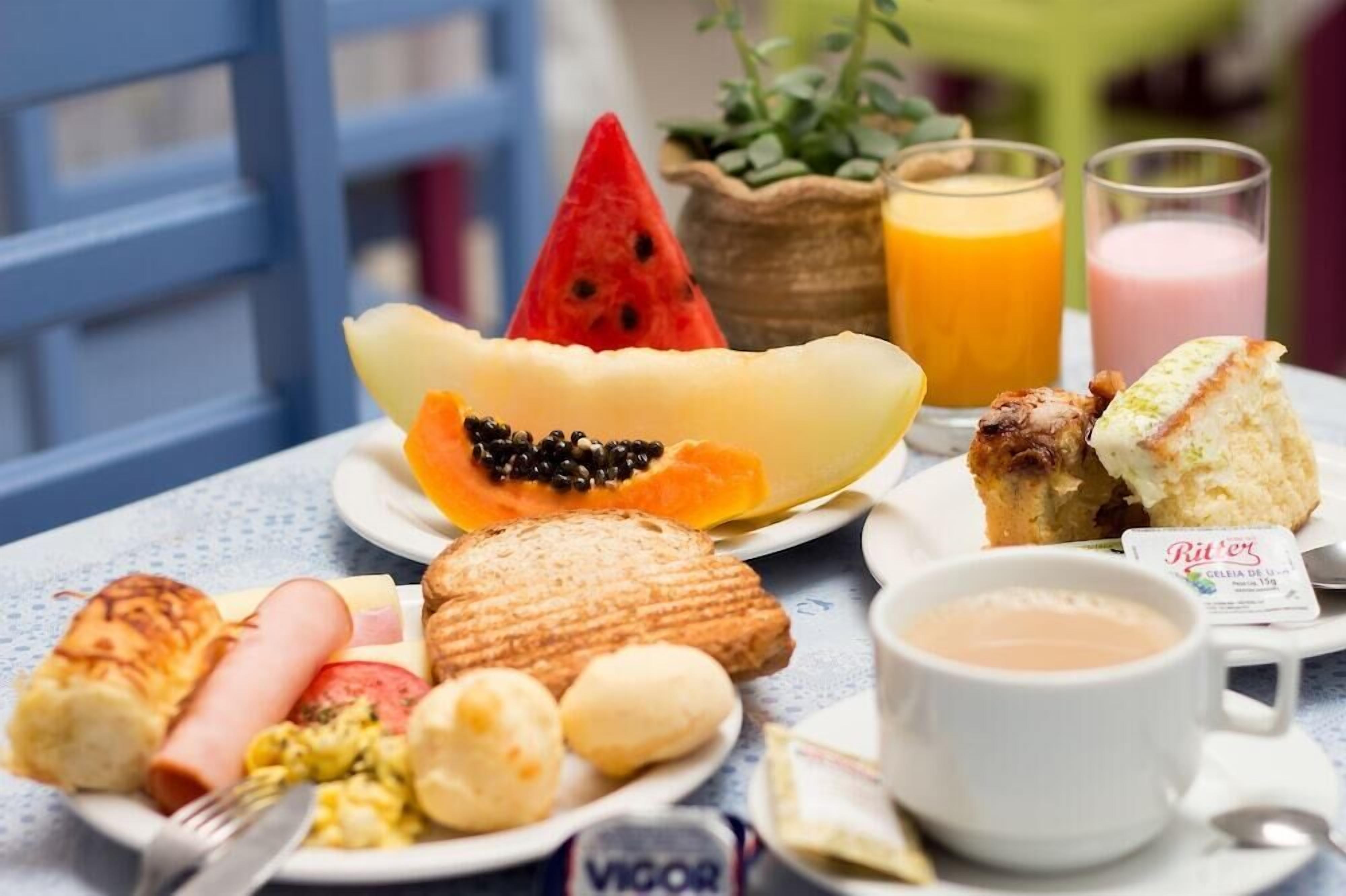 Een ontbijttafel met verschillende soorten eten, zoals brood, gebak en een stuk watermeloen.
