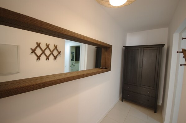 A hallway with a large mirror, a dark wooden wardrobe, and a small decorative wall piece. - 108 - Paraje de Los Lances (Tarifa)