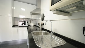 A modern kitchen with white cabinets, a stainless steel sink, and a built-in microwave. - 108 - Paraje de Los Lances (Tarifa)