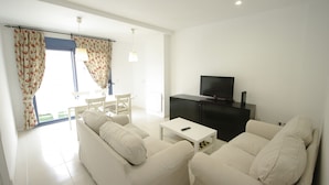 A modern living room with a sofa set, a television, and a dining area with a table and chairs. - 108 - Paraje de Los Lances (Tarifa)