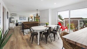 A modern kitchen with a central island, white cabinetry, and a view of the city through large windows. - HOT TUB! Sunset Views. Walk to Beach. Pet Friendly. Sleeps 10! (Westport)