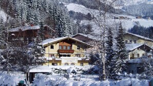 Un pueblo cubierto de nieve con construcciones tradicionales de madera, incluyendo un edificio amarillo destacado con balcón.