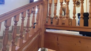 Una escalera de madera con barandilla, un cuadro enmarcado en la pared y una guirnalda decorativa.
