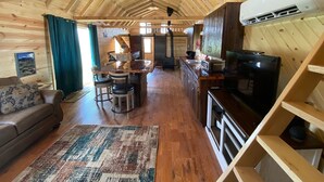 A wooden cabin interior with a kitchen, dining area, and living room.