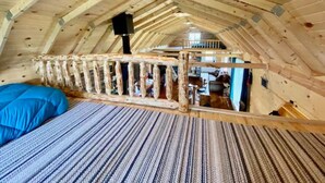 An attic bedroom with a sloped ceiling, a wooden staircase, and a bed with blue bedding.