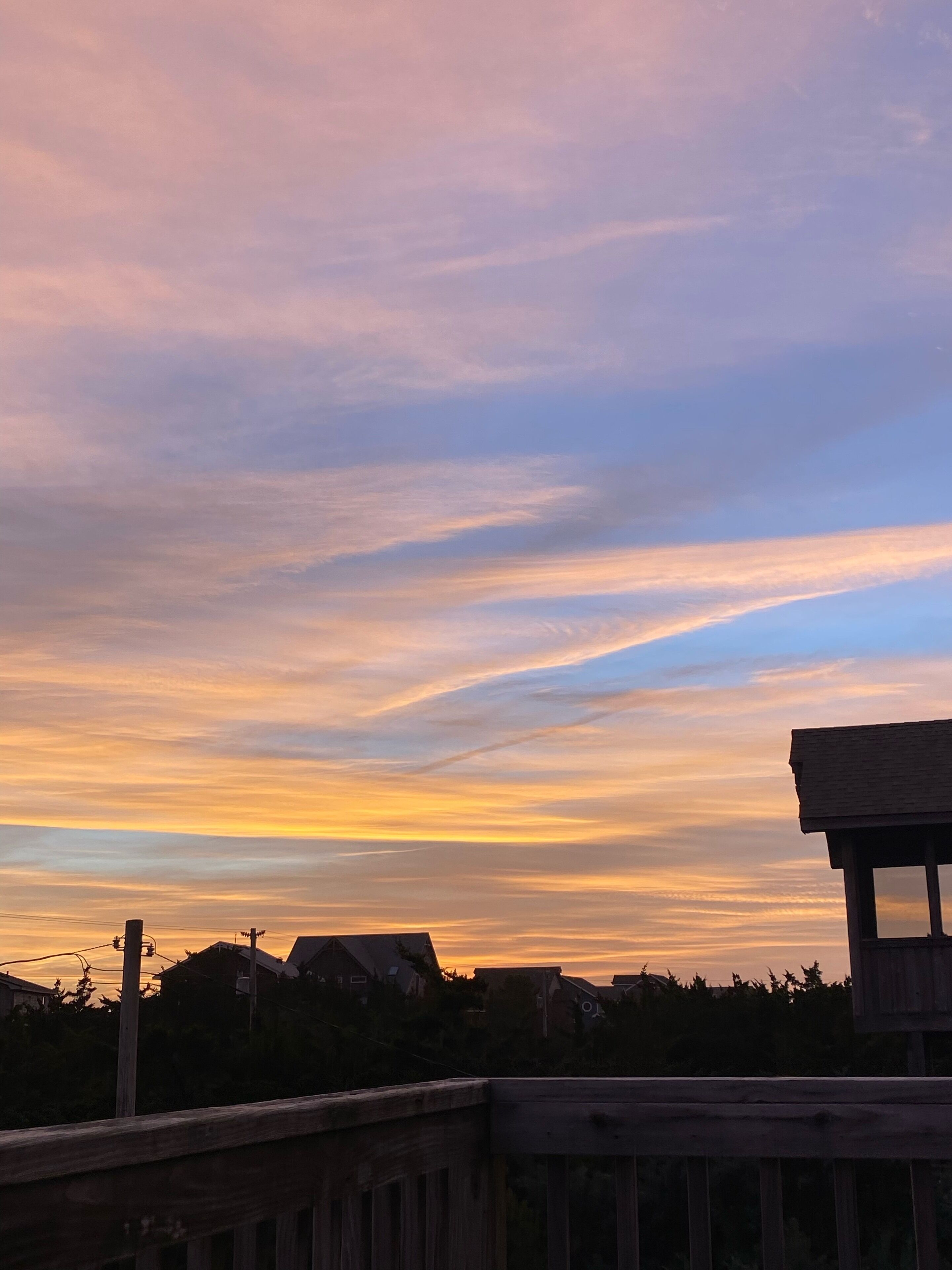 Une vue sur le coucher de soleil, avec une terrasse en bois et des maisons en arrière-plan.
