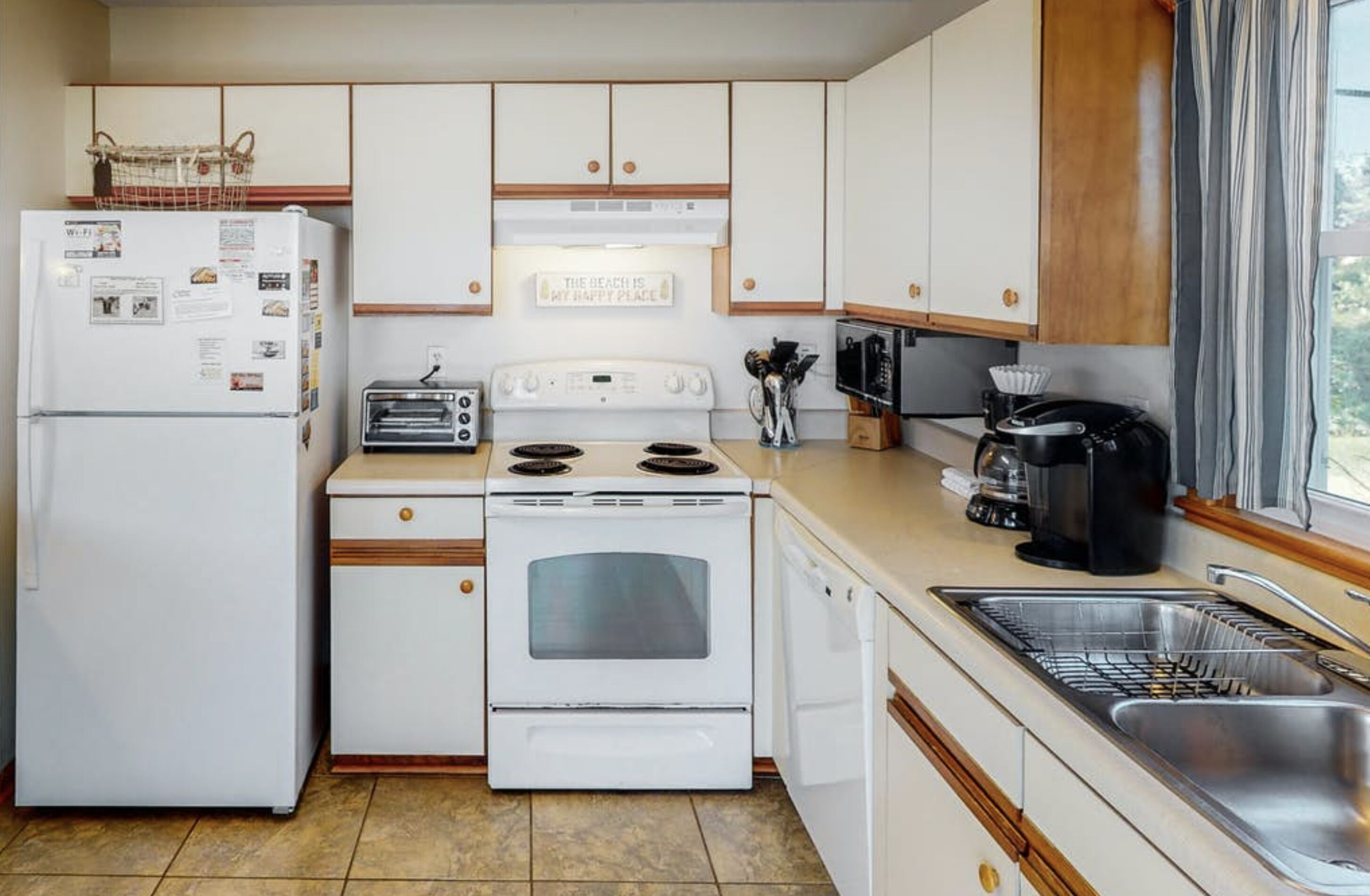 A compact kitchen with a refrigerator, stove, oven, toaster, and coffee maker.