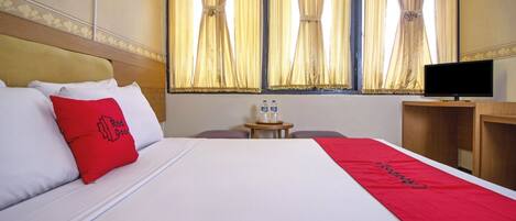 Habitación de hotel con cama, televisor y una pequeña mesa con botellas de agua.