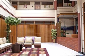 A spacious lobby with a high ceiling, a seating area with sofas and armchairs, a patterned rug, and a large poster of the Eiffel Tower. - RedDoorz near Hyperpoint Pasteur 2 (Bandung)