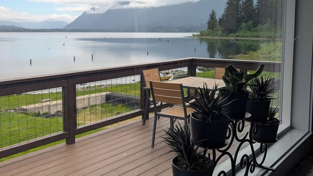 A balcony with a view of a lake, a wooden deck, and potted plants.