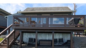 A two-story house with a deck, a staircase, and a fenced area.