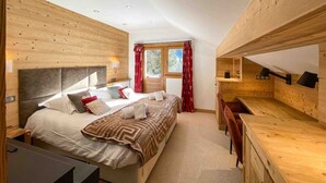 A bedroom with a large bed, a desk, and a window with curtains. - Chalet ski in / out avec vue, emplacement fabuleux (Meribel Les Allues)