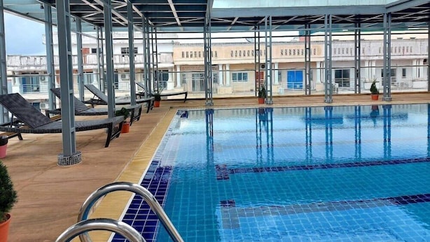 An indoor swimming pool with clear blue water, surrounded by lounge chairs and potted plants.