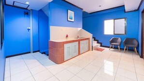 A modern room with blue walls, a kitchen area with cabinets, a sink, and two chairs. - Diyana Residence (Pattaya)