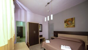 A hotel room with a bed, a desk, a wardrobe, and a painting on the wall. - Hotel Sabatino (Follonica)