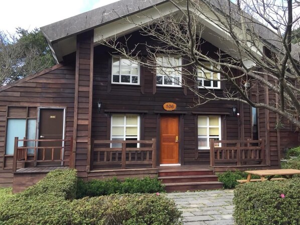 A two-story wooden cabin with a front porch, a wooden door, and a number '106' sign. - Yangmingshan Jing Shan Recreation Area (Taipei)