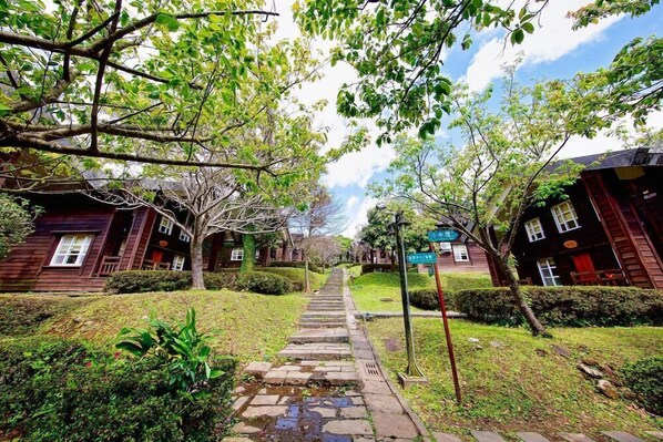 A pathway leading to traditional wooden buildings with a small garden and a signpost. - Yangmingshan Jing Shan Recreation Area (Taipei)