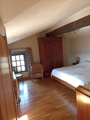 A bedroom with a wooden bed, a chair, a wardrobe, and a window with curtains. - Authentic Mas in the middle of a magnificent property. Impressive view. (Cabris)