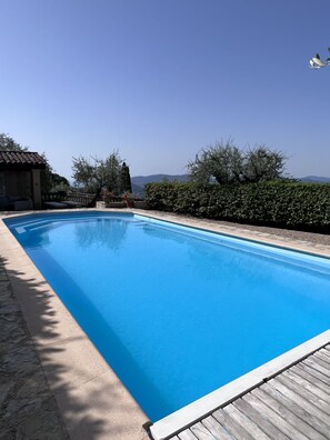 A rectangular swimming pool with a wooden deck edge, surrounded by a stone patio and a hedge. - Authentic Mas in the middle of a magnificent property. Impressive view. (Cabris)