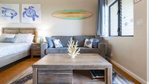 Un dormitorio acogedor con cama, sofá, mesa de centro y obras de arte en la pared.