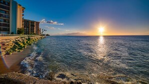 Un hotel frente a la playa con vista al océano y al atardecer.