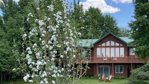 A wooden house with a balcony, surrounded by a well-maintained lawn and trees. - Welcome to CoCo Ranch Mtn Stay – Your Private Teton Valley Escape! (Victor)