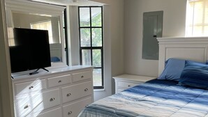 A bedroom with a bed, dresser, television, and a ceiling fan. - Manatee Manor. Waterfront, dock, stilted home. Renovated June '23.  (Homosassa)